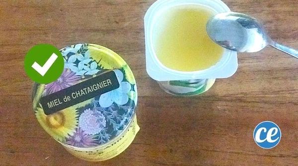 Un pot de miel de châtaignier avec un yaourt nature avec du miel et une petite cuillère