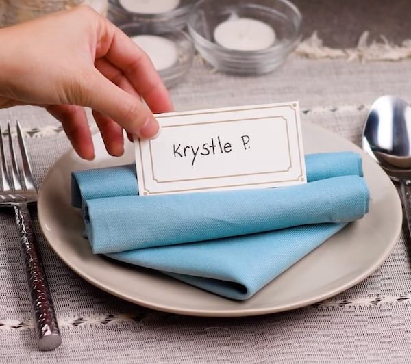 Guardanapo azul dobrado em cartões de lugar em um prato