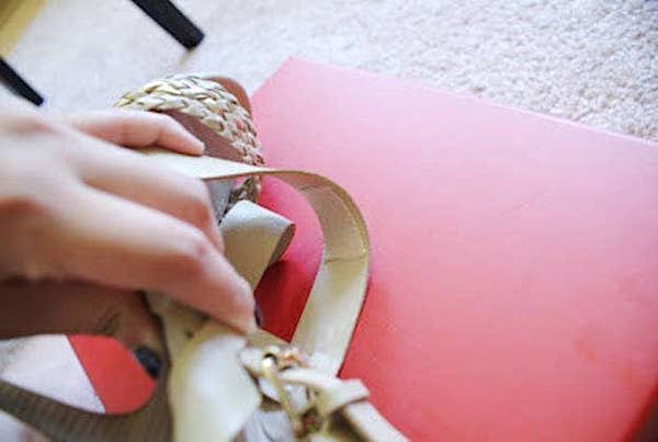 Une main qui colle une bande de moleskin adhésive à l'intérieur d'une chaussure.