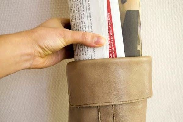 Une main qui insère du papier journal dans une tige de botte en cuir.