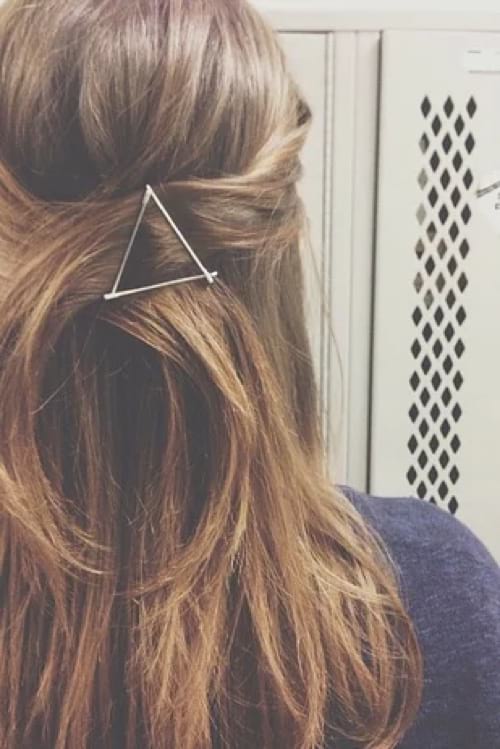 Cheveux longs bruns attachés en arrière avec une barrette en triangle faite avec des épingles