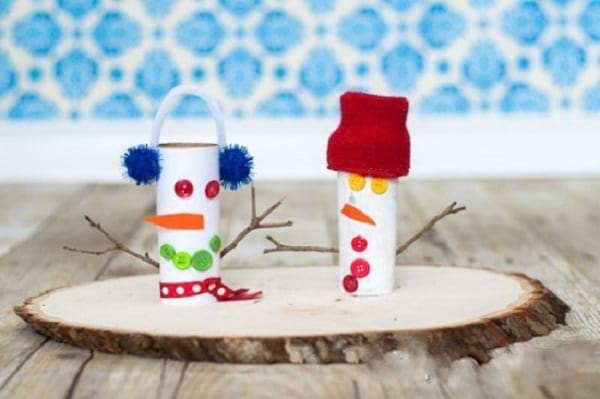 Bonhomme de neige fait à partir de rouleaux papier toilette collés sur une planche de bois décorative