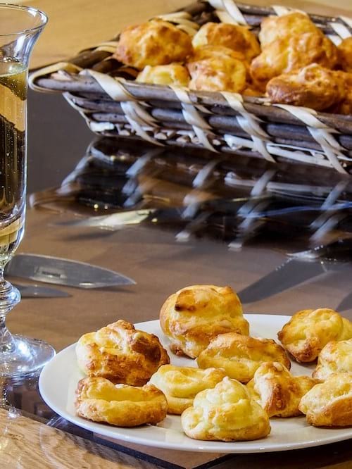 Des gougères au fromage dans une assiette à côté d'un verre de champagne