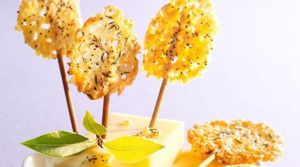 des sucettes faites avec du gruyère et des cure-dents pour l'apéro présentées sur un morceau de fromage