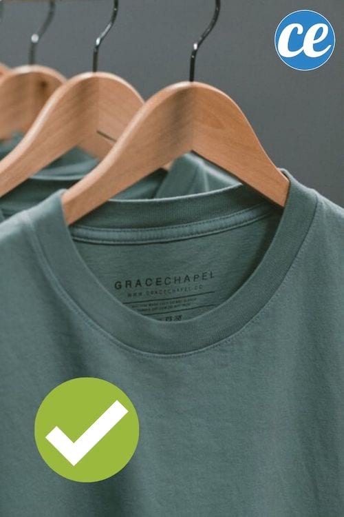 Des t-shirts gris sur cintres en bois.