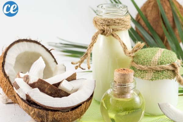 demi noix de coco avec un flacon d'huile de coco sur une table verte