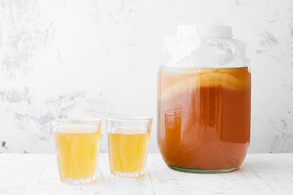 Un bocal de Kombucha fait maison et 2 verres sur la table en bois