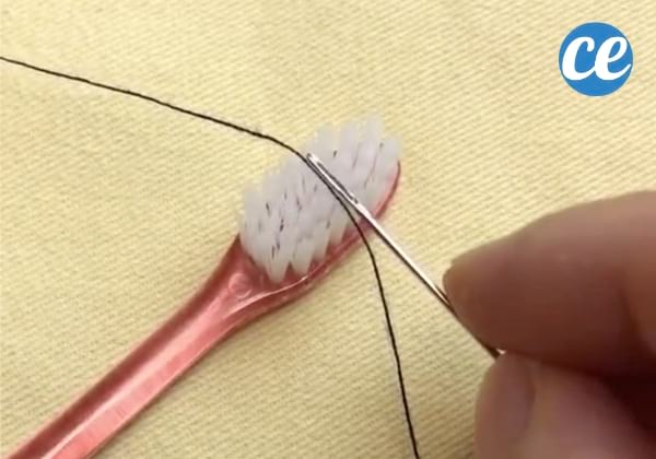 Aiguille avec un trou posé sur le fil et la brosse à dents