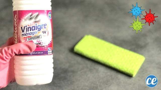 Une main dans un gant rose de nettoyage pour désinfecter avec du vinaigre blanc