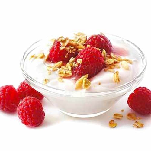 Un bol de yaourt avec des fruits rouges sur fond blanc.