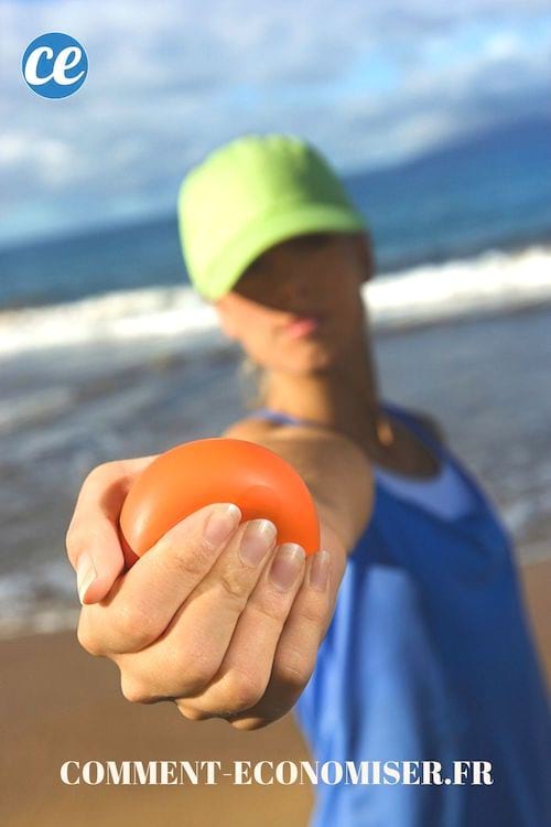 Une femme qui tient une balel antistress rouge en main, à la plage.
