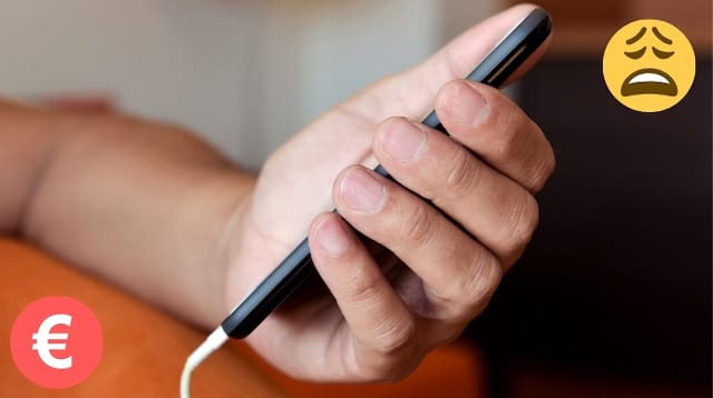 Une main sur un canapé qui tient un smartphone en train d'être chargé 