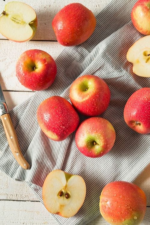Des pommes rouges sur un torchon rayé.
