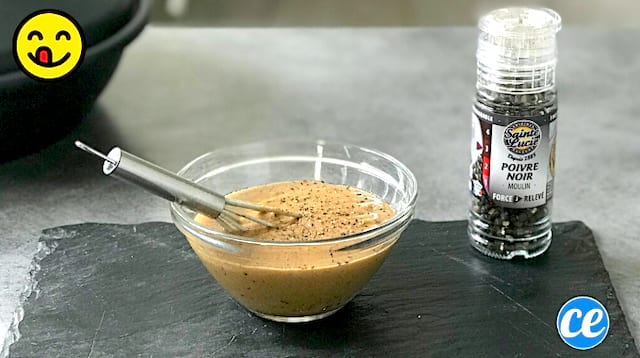 De la sauce au poivre faite maison dans un récipient posé sur une table avec un moulin à poivres