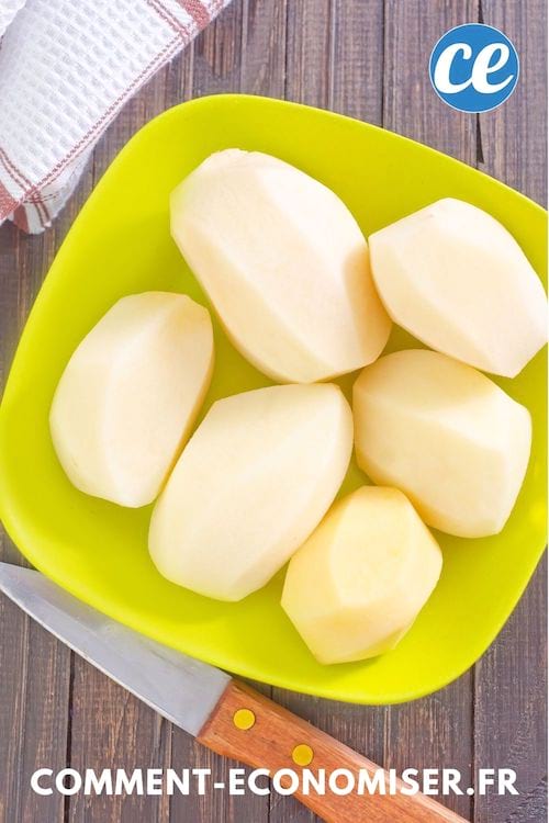 Pommes de terre épluchées dans un bol jaune sur une table en bois.