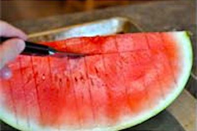 Un couteau qui coupe des tranches horizontales dans une pastèque.