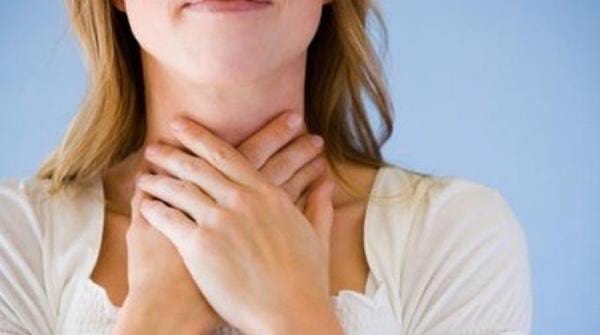 Une personne qui pose ses mains sur la gorge parce qu'elle a mal à la gorge