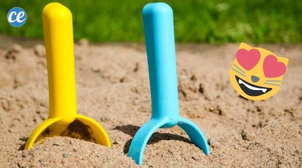 Une pelle jaune et une pelle bleue dans un bac à sable extérieur.