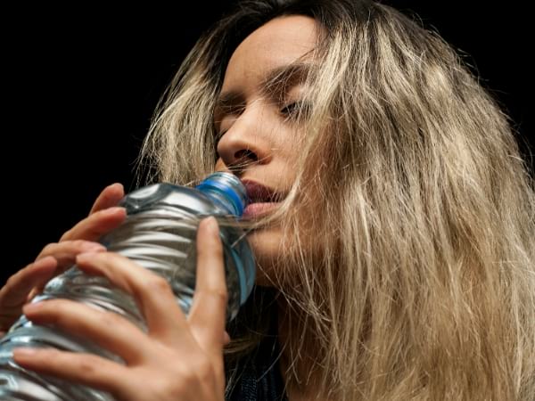 Une femme boit de l'eau dans une bouteille