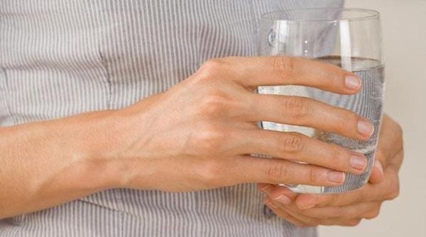 Une personne tient un verre plein d'un mélange d'eau et de chlorure de magnésium