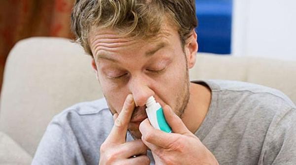 Un jeune homme utilise un spray nasal
