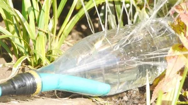 Arroseur dans un jardin avec une ancienne bouteille en plastique