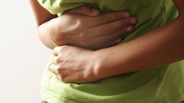 Une femme se tient le ventre à cause de douleurs dues à la constipation