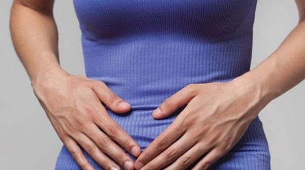 Une femme se tient le ventre à cause de la douleur