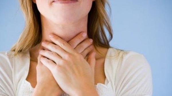 Una persona che si mette le mani sulla gola perché ha mal di gola