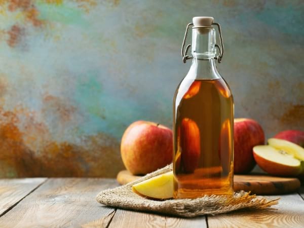 Une bouteille de vinaigre de cidre avec des pommes pour aider la perte de poids
