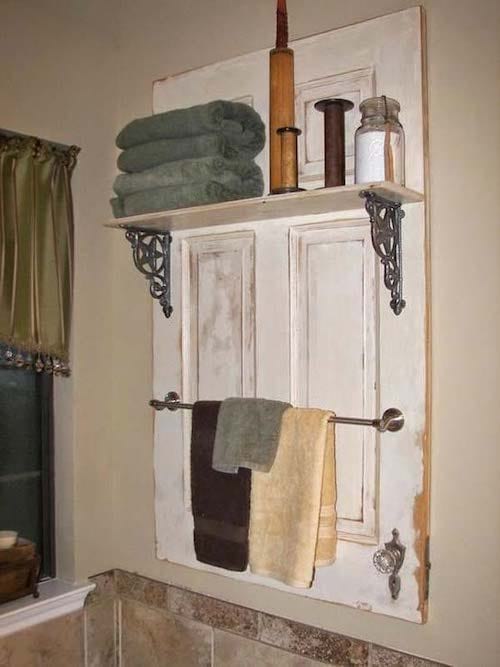 Ancienne porte blanche accrochée au mur de la salle de bain pour créer un espace de rangement