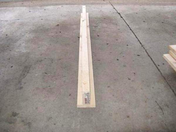 2 planches en bois assemblées en forme de T, sur un sol en béton.