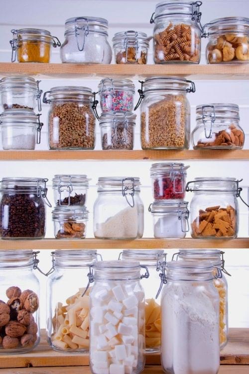 Des bocaux d'aliments secs sur des étagères en bois.