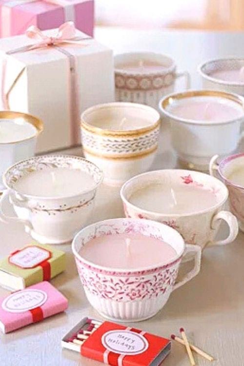 Des bougies faites maison dans des vieilles tasses à thé, avec des cadeaux.