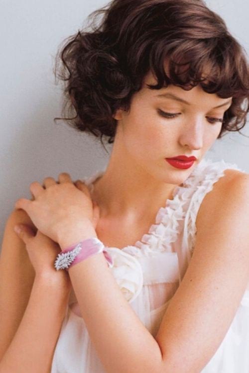 Un beau bracelet fait avec un ruban et une broche sur le poignet d'une jeune femme.