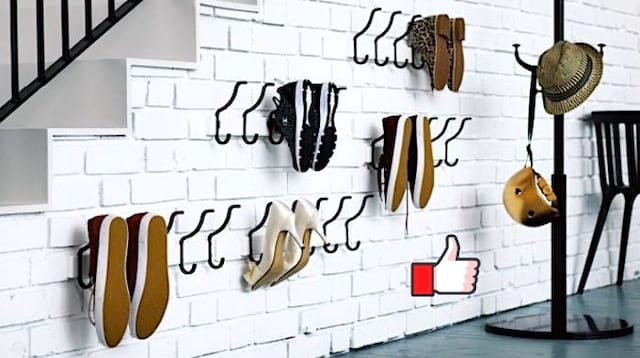 Des chaussures accrochés sur un porte manteau sur un mur blanc