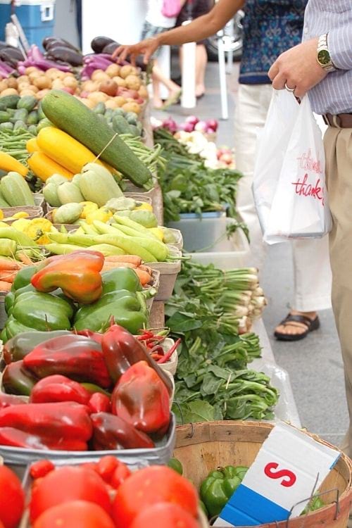 Los clientes compran frutas y verduras de temporada en un mercado de agricultores.