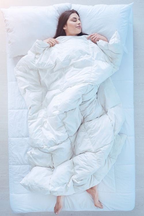 Une femme qui dort dans un lit avec une couette en duvet.