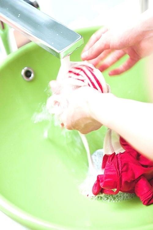 Une femme qui lave des vêtements à la main dans un lavabo.