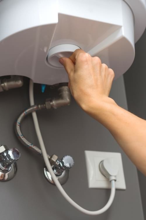 Une main qui règle chauffe-eau à une température plus basse pour économiser