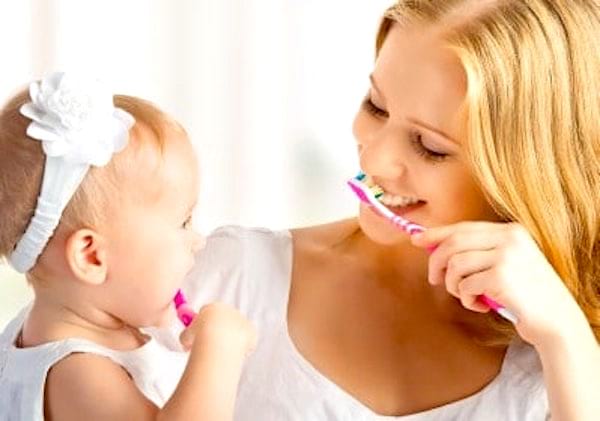 Une jeune femme et un nourrisson se brosse les dents.
