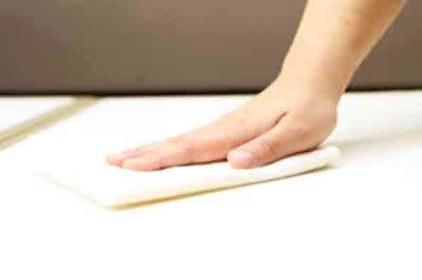 Une main qui passe un chiffon imbibé d’eau oxygénée pour raviver le blanc d'une nappe.