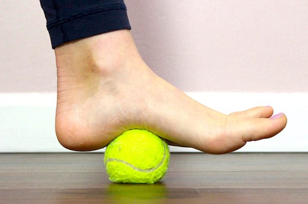 Un pied qui relâche la tension du fascia plantaire avec une balle de tennis.