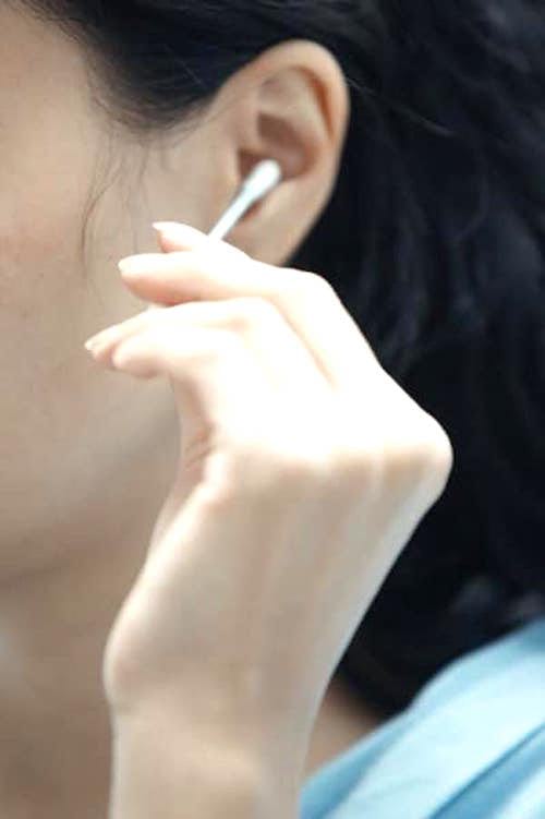 Une femme qui se nettoie l'oreille avec un Coton-Tige.