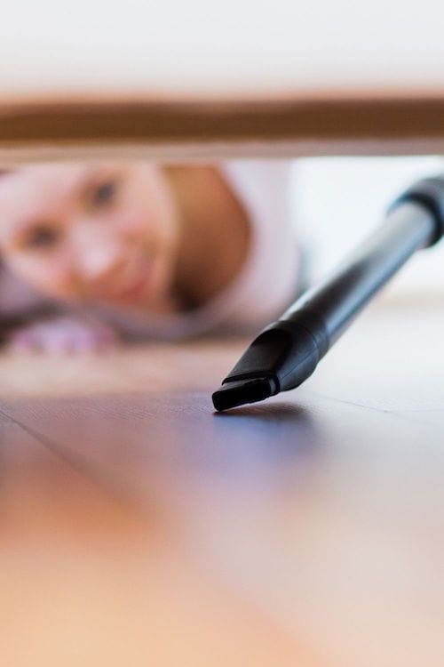 femme qui passe l'aspirateur sous les meubles