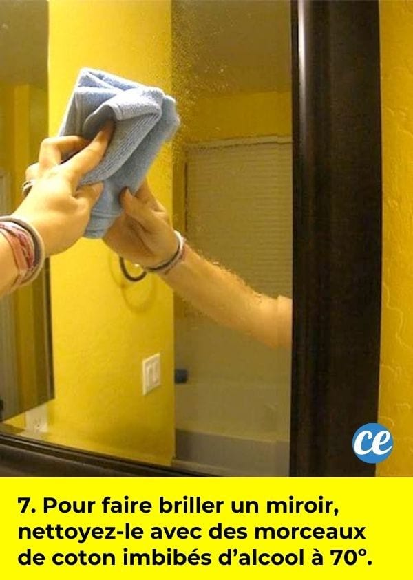 Une main qui nettoie un miroir de salle de bain avec un chiffon microfibre.