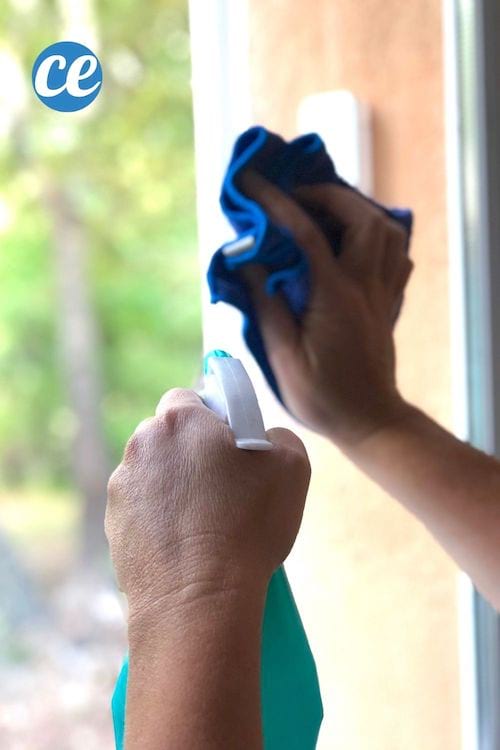 Une personne en train de nettoyer les vitre avec un chiffon et un spray d'alcool ménager