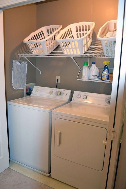 A slanted shelf with baskets above a washing machine