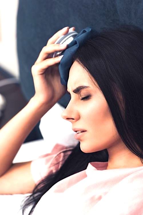Une femme qui applique une poche de glace pour soulager la migraine.