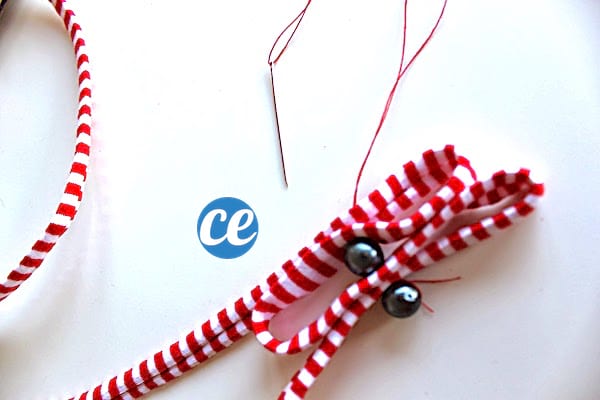 explication pour faire une décoration de Noël DIY avec un ruban, des perles et une aiguille